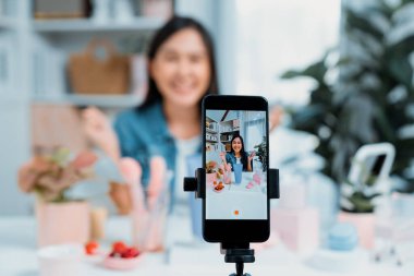 Genç ve güzel Asyalı bir kızın nemlendirici vücut kremi ürününü inceleyerek sosyal medyada koluyla en çok satanlar listesine giren canlı bir cilt testi yaptığı seçmeli bir odak telefonu. Taktik.