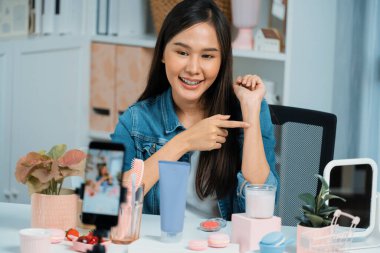 Genç, güzel Asyalı kozmetik makyaj ruju matte pastel rengini modern odadaki sosyal medyada kol testi tanıtımında en çok satanlar listesinde gösteriyor. Taktik.