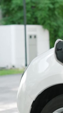 İlerici adam evindeki elektrikli aracın aküsüne emisyonsuz güç bağlantısı kuruyor. Elektrikli araç elektrik istasyonundan EV araba aküsüne kabloyla şarj oluyor.