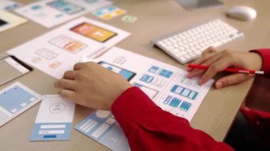 Mobil uygulama için kullanıcı arayüzü prototipini ofis çalışanlarına sunan harika bir şirket çalışanı. UX UI tasarımcısı kağıt üzerinde simge tasarımının işlevini açıklıyor. Sinerjik