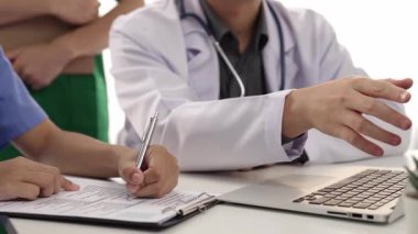 Hasta için hastane masasında çalışan ve tıbbi tedavi planlayanlardan oluşan profesyonel bir ekip. Takım çalışması başarılı hastalıklara ve hastalıklara yol açar. Ağır çekim. Katı.