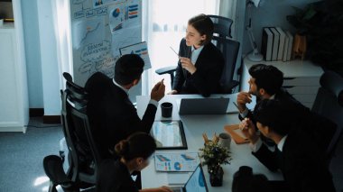 Akıllı yönetici yöneticisinin üst görünümü, beyaz tahtayı işaret ederken çeşitli takımlara satışların arttığını gösteriyor. Bir grup insan borsa yatırım verilerini analiz ediyor. Zaman aşımı. Müdürlük.