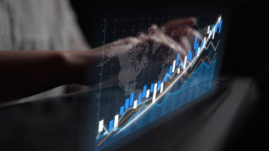 A close-up of hands typing on a laptop with a dynamic stock market graph overlay and world map, illustrating digital finance and professional analysis in action. Copula