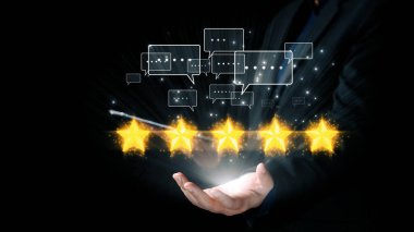 Bir iş adamı zarif bir şekilde elinde beş yıldızla, dijital alemdeki mükemmelliği ve müşteri hizmetlerindeki memnuniyeti simgeleyen parlak geri bildirim baloncukları sunar. Dörtgen