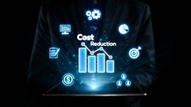 A businessman presents a tablet showcasing a cost reduction graph surrounded by various icons, symbolizing efficient financial strategies in a digital environment. Qubit