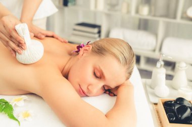 Sıcak bitkisel top spa masaj vücut tedavisi, masör kadın vücuduna nazikçe şifalı bitki torbası bastırıyor. Aromaterapi dinlenme sükuneti ve sükuneti kaplıca salonundaki atmosferi aydınlatıyor. Sessiz.