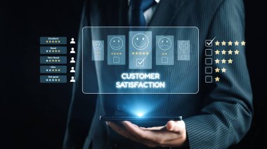 Bir iş adamı müşteri memnuniyeti oranlarını gösteren bir akıllı telefon tutar. Görüntü, günümüz iş ortamındaki hizmet kalitesinin değerlendirilmesinde geri bildirimin önemini gösteriyor. Dörtgen