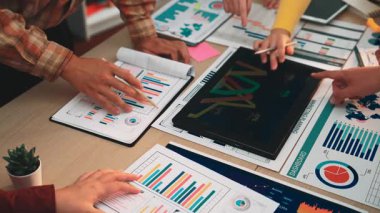 A team of professionals engaged in a discussion around financial charts and data. They analyze insights to guide business strategy and improve performance metrics. SACTR