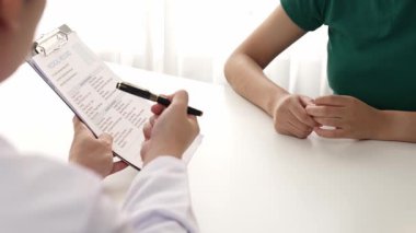 Klinikteki ya da hastane ofisindeki doktor randevusuna katılan hasta, tıbbi tedavi seçeneklerini tartışıyor ve muayene sonuçlarını ya da hastalıkla ilgili tıbbi kayıtları açıklıyor. Ağır çekim. Katı.