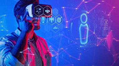 A young man uses a virtual reality headset, fully immersed in a colorful digital landscape. He interacts with virtual avatars and data, showcasing modern technology trends. Raster