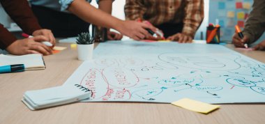 Değişik bireylerin ellerini gösteren dinamik bir sahne beyin fırtınasına aktif olarak katılan, büyük bir kağıt üzerinde fikirler üreten. SACTR