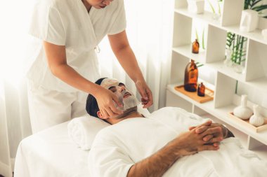 Kaplıca salonunun sakin, modern gündüz atmosferi. Kadın müşteri yüz maskesi takarak kendini yenilemeye çalışıyor. Yüz bakımı ve güzellik kozmetolojisi prosedürü. Sessiz.