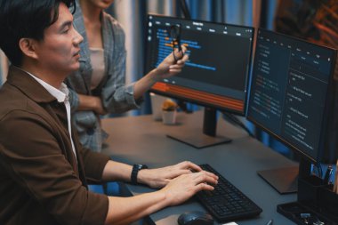 Bilgi teknolojisi geliştiricileri modern ofisteki neon ışık odasında verileri çevrimiçi olarak çalıştıran akıllı web sitesi geliştirme kodlayıcı sistemine işaret ediyorlar. İnfobahn.