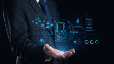 Takım elbiseli bir işadamı, veri güvenliğini simgeleyen parıldayan dijital bir kilit taşıyor. Fütüristik arka planda modern siber güvenlik temalarını gösteren çeşitli teknoloji simgeleri yer alıyor. Dörtgen