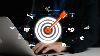 A businessman working on a laptop with a vibrant target icon surrounded by analytical elements, symbolizing goal achievement and strategic business planning. Qubit