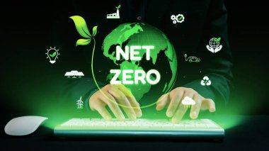 This image depicts a person typing on a keyboard with a glowing green planet and net zero text, symbolizing a commitment to sustainability and a greener future. Qubit
