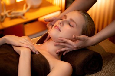 Beyaz kadın stres önleyici kafa masajı yapmaktan ve lüks otel veya otelde sıcak mum ışığında yüz güzelliği eğlencesi yapmaktan zevk alıyor. Sessiz.