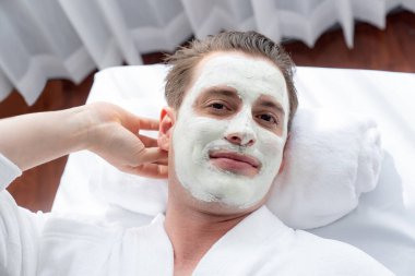 Kaplıca salonunun sakin atmosferi, insan müşterisi modern gün ışığında lüks yüz kremi masajıyla kendini yenileme zevkine kapılıyor. Yüz bakımı ve güzellik konsepti. Sessiz.