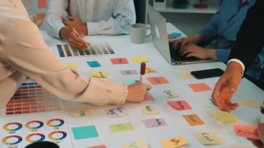 A diverse team collaborates in a bright office setting, using colorful sticky notes and digital devices to brainstorm and organize ideas effectively. SACTR