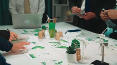 A dynamic scene of a collaborative business meeting where professionals discuss eco-friendly concepts and strategies in a modern office setting with teal decor. SACTR