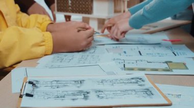 Close-up of hands actively planning architectural layouts during a creative workshop, showcasing sketches, notes, and collaboration in a vibrant workspace. SACTR