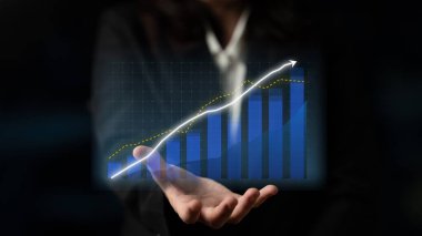 A professional businesswoman presents a digital growth graph with an upward trend, symbolizing success and achievement in a corporate environment. Impute