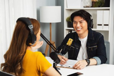 Gülümseyen radyo etkili sunucusu kulaklık takıyor kadın konuşmacı ile röportaj yapıyor sosyal medya internet sitesinden dinleyicilere bilgi paylaşıyor stüdyo kaydında sabah canlı yayın kanalı. İnfobahn.