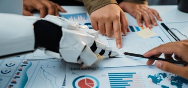 Bu resim, insanlar ve robotlar arasındaki işbirliğini modern çalışma ortamında yakalar, grafikler ve grafiklerle veri analizlerini gösterir, takım çalışmasını ve teknolojisini vurgular. Noogenesis