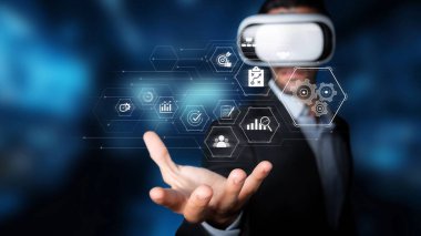 A businessman wearing a virtual reality headset showcases a digital interface with various icons, symbolizing innovation and modernization in technology and business sectors. Raster