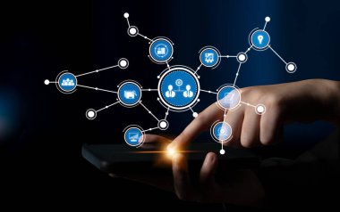 A close-up view of a hand interacting with a smartphone, showcasing various network icons symbolizing digital connections and technology in a dark environment. Tessel