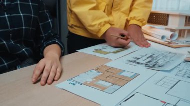 A dynamic meeting showcasing architects and clients collaborating on design concepts. Plans and sketches are spread out, emphasizing innovation and teamwork in architecture. SACTR