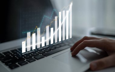 A modern laptop with financial graphs displayed on the screen, representing business analytics and data analysis in a professional work environment. Impute