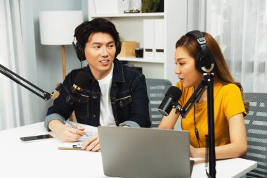 Gülümseyen radyo etkili sunucular, kulaklık takarak sosyal medya kanalından canlı yayın yapıyorlar ve sabah saatlerinde stüdyo kaydında dinleyicilere konu ve dizüstü bilgisayar üzerinden konuşuyorlar. İnfobahn.