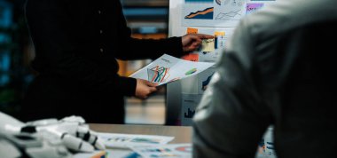 Takım üyeleri bir veri analiz oturumunda modern ofis ortamında çizelge ve grafikleri tartışıyor, işbirliği ve stratejik planlamayı vurguluyorlar.