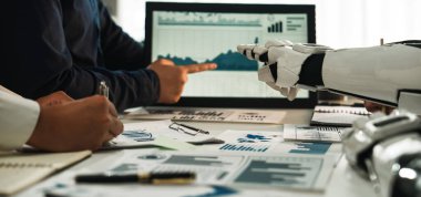 Modern bir ofiste robotla işbirliği yapan bir insanı tasvir eden eşsiz bir sahne. Mali raporlar ve veri analizleri ekranda ve tabloda gösteriliyor. Noogenesis