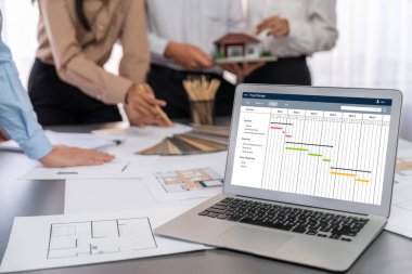 İç mimar tasarımcı grubu, daha kesin tasarım için planlar ve dizüstü bilgisayar ekran mimari yazılımı üzerinde birlikte tartışıyorlar. Modern ev tasarımı ve yenileme. İçgörü