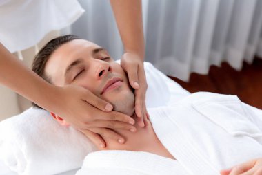 Beyaz adam stres önleyici kafa masajından ve lüks bir tatil beldesi veya otel spa salonundaki modern ışık ortamında yüz güzelliği eğlencelerini şımartmaktan hoşlanıyor. Sessiz.