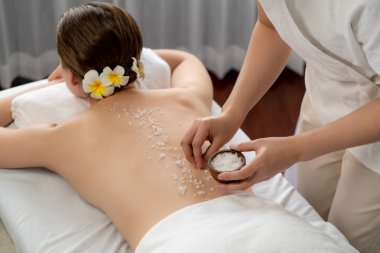 Lüks spa salonlarında sıcak mum ışığında cilt bakımı yaptıran kadın müşteri. Sağlık Spa vücut fırçasında tuz temizleme güzellik tedavisi. Sessiz.
