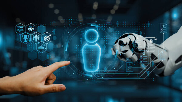 A human hand points towards a glowing holographic figure as a robotic arm shows a digital interface, illustrating advanced technology concepts in a modern workspace. Auvana
