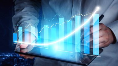 A business professional examines financial data on a digital tablet, surrounded by futuristic graphs and statistics, showcasing growth and innovation at night. Copula
