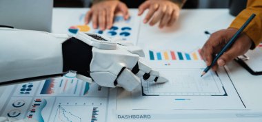 Bir insan ve bir robot el çeşitli veri görselleştirmeleri ve raporları üzerinde işbirliği yaparak, iş dünyasındaki analitik süreçlerin şekillendirilmesinde modern teknolojilerin rolünü vurgular. Noogenesis